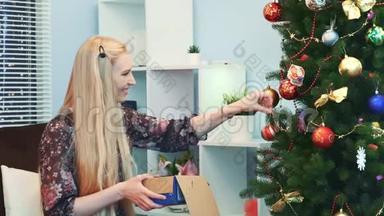 快乐的女人把玩具挂在圣诞树上，从盒子里<strong>拿出来</strong>